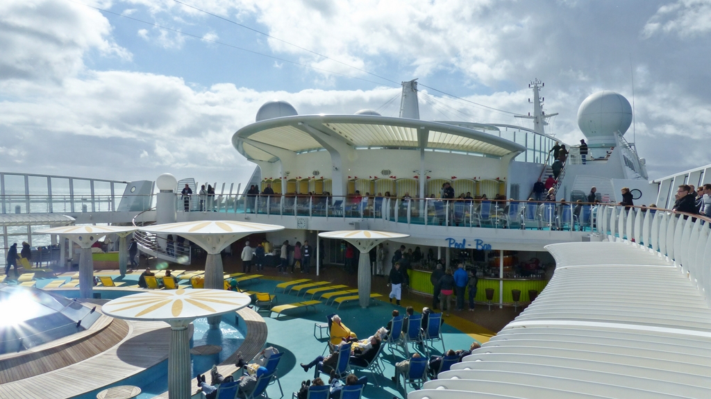Blick auf das obere Deck, wo eine Poolbar ist. einige sitzen auf Stühlen und genießen die Sonne